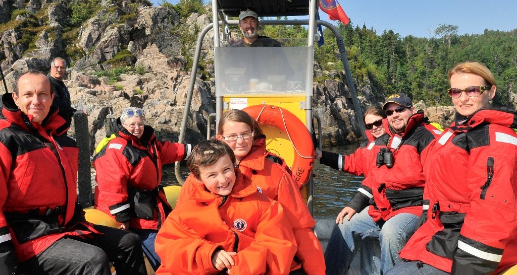 Une famille en habit rouge dans le zodiac, capitaine à la console derrière