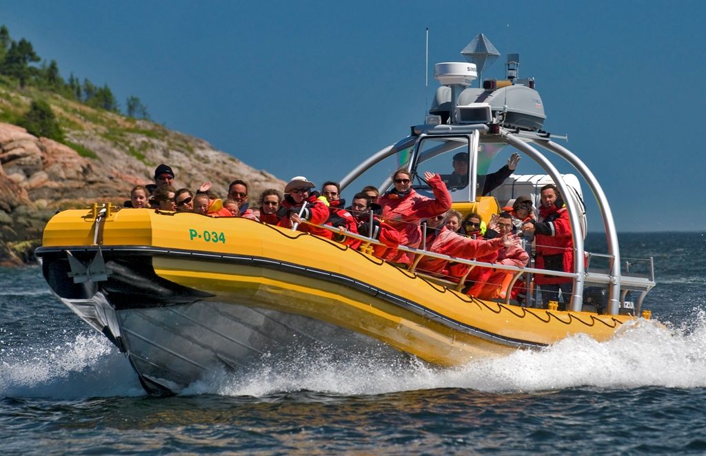 Un zodiac jaune rempli de passagers en habits rouges, à vive allure