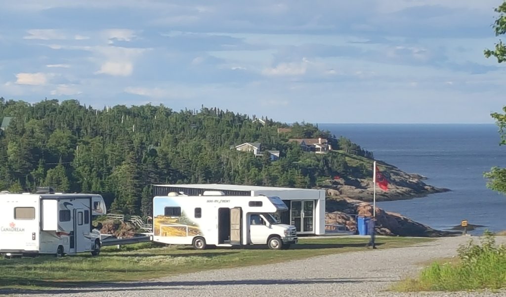 Des véhicules récréatifs garés sur la pointe, face au fleuve